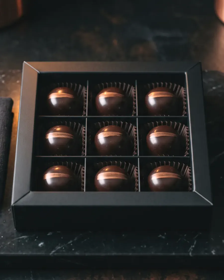 Polished dark chocolate bonbons in a matte black box